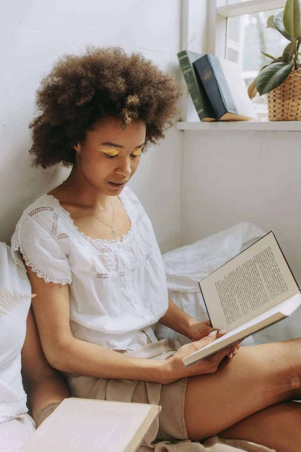 Woman sitting on a bed reading a book