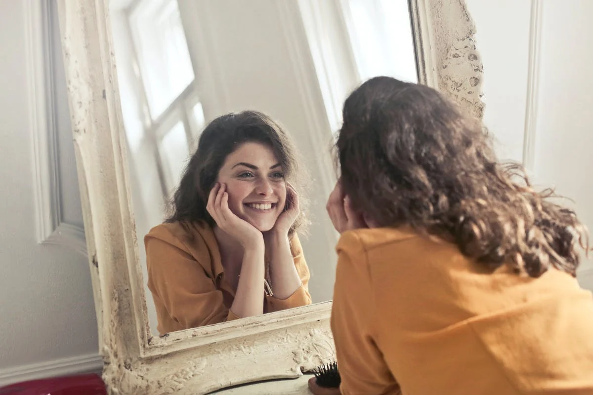 woman looking in the mirror comparing herself to herself