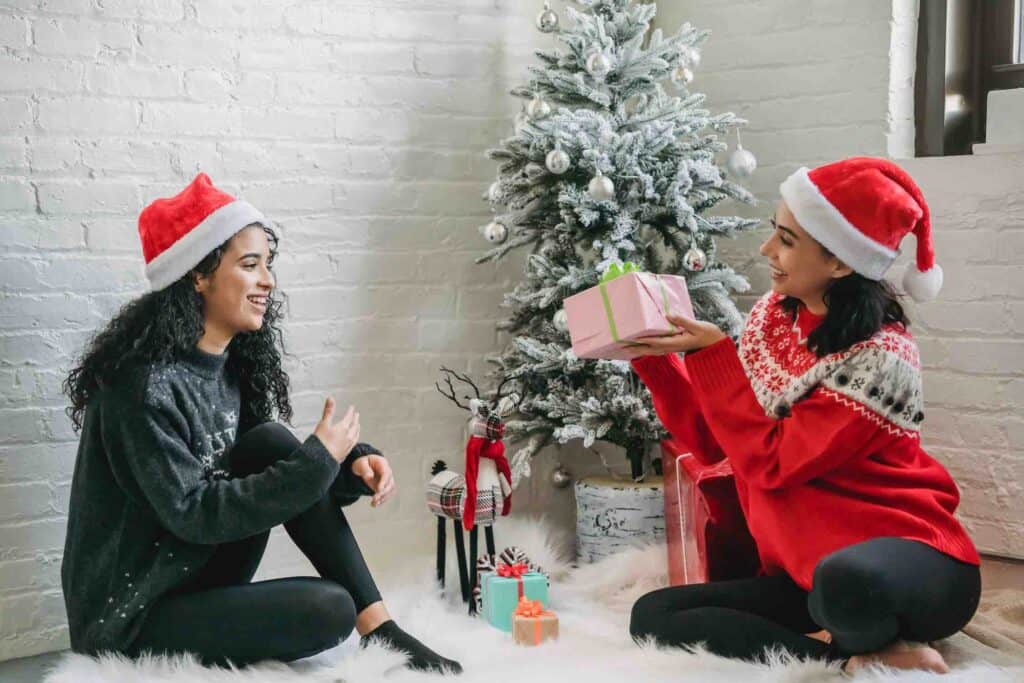 2 women exchanging Christmas gifts bought with winter side hustle extra cash